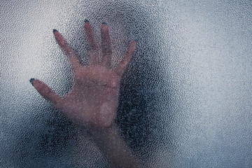 Halloween female hand behind transparent glass background as sil