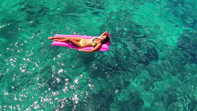 Beautiful Young Ethnic Pacific Islander Woman In Bikini Floating on Pink Inflatable Raft in Crystal Ocean in Hawaii. Summer Fun Vacation Lifestyle. Ethnic Diverse Beauty Pacific Islander 