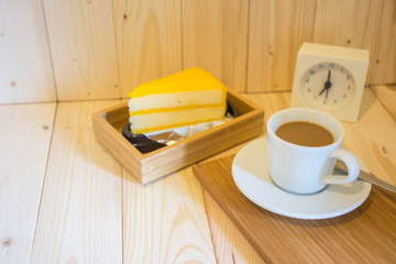 Coffee in the morning with orange cake on wood background