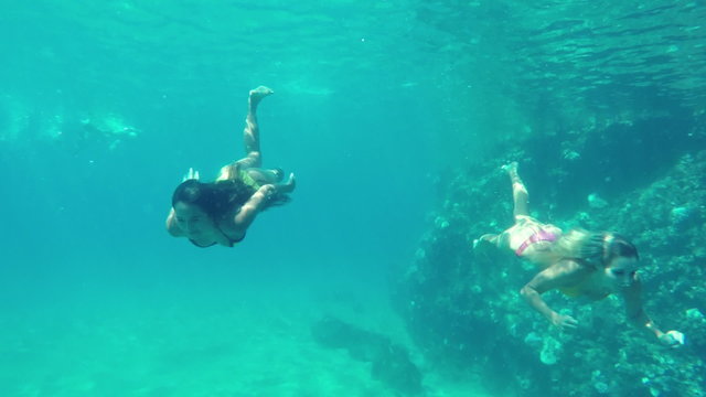 Beautiful Girls in Bikinis Swimming Underwater in Pacific Ocean. Hawaiian Ethnic Girl with Young Blonde Girl Friend. Summer Fun Lifestyle.
