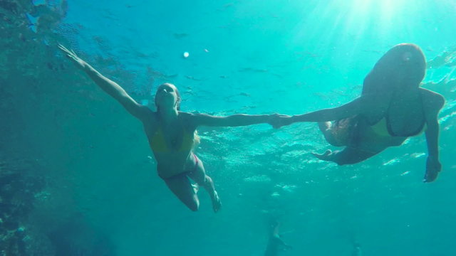 Slow Motion Beautiful Girls in Bikinis Swimming Underwater Holding Hands in Pacific Ocean. Hawaiian Ethnic Girl with Young Blonde Girl Friend. Summer Fun Lifestyle.