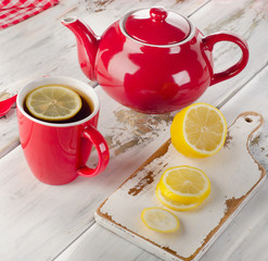 Teapot and cups with lemon slices on wooden table.