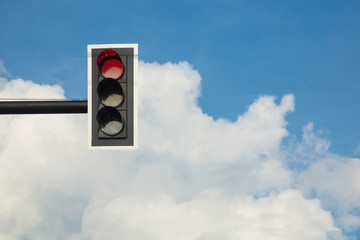 Red color on the traffic light with a beautiful blue sky in background
