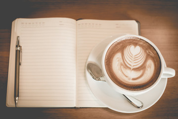 latte art coffee and notebook on the table at restaurant