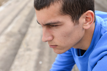 Obraz premium Teen boy sitting on stairs and looking at the camera
