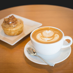 Apple cinnamon roll served with latte coffee on the table at res