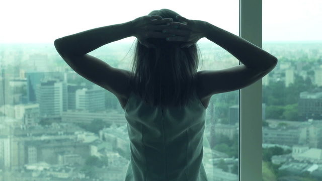 Young businesswoman stretching her arms and admire view from window 
