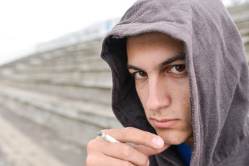 Young man in depression smoking a cigarette on a stadion and loo