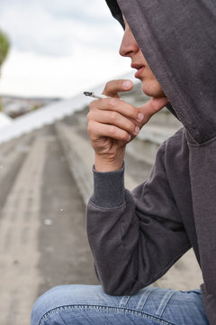 Young man in depression smoking a cigarette on a stadion. Concep