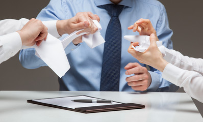 Business people cruelly tearing documents, gray background