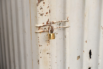 close up of a rusty steel door securely locked with a golden pad