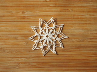 Crocheted snow flake on a wooden background.