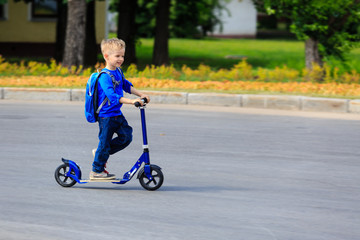 little boy riding scooter in the city