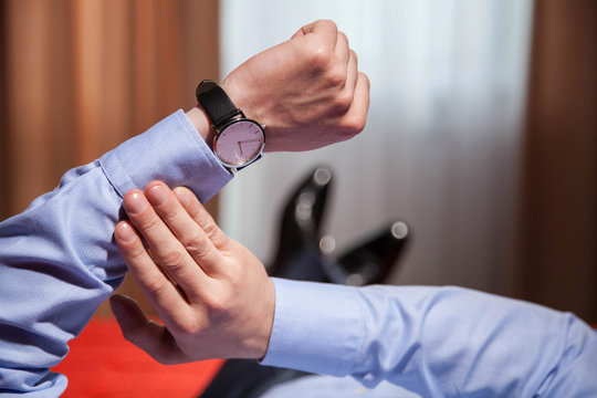 Businessman looking at the wristwatch and lying on the bed