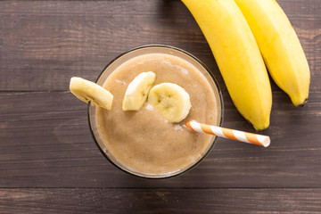 Banana smoothie and fresh banana on wooden background. Top view