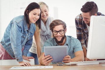 Smiling business people using digital tablet at computer desk 