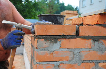 Bricklayer Using a Bricklaying Hammer to Build New Red Brick Wall Outdoor. Bricklaying Basics Masonry Techniques.