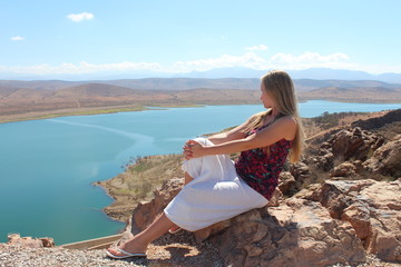 A young woman sit on the rock. 
