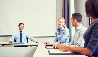 group of smiling businesspeople meeting in office