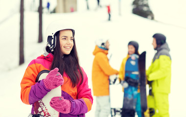 happy friends in helmets with snowboards