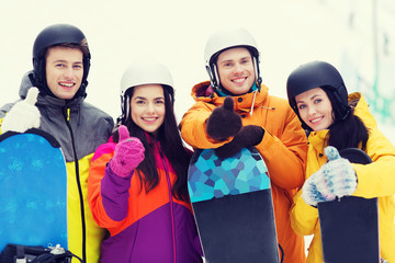 happy friends in helmets with snowboards