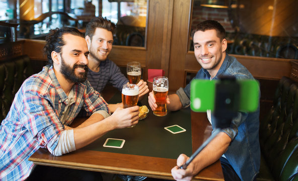 friends taking selfie and drinking beer at bar