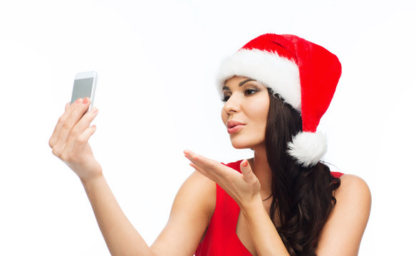 woman in santa hat taking selfie by smartphone