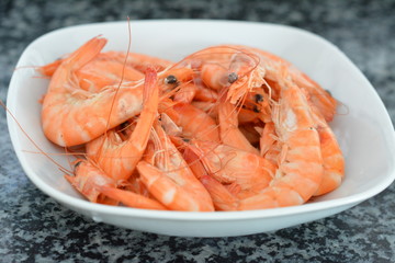 red lobster in white plate ready 
on the gray granite kitchen surface
