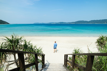 Gateway to paradise, man standing looking at idyllic tropical beach lagoon in Okinawa, tropical Japan