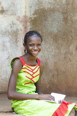 Education Symbol: In Bamako (Mali), a young schoolgirl is concentrated while drawing on her exercise book. Smiling African black Girl in a school environment outside her classroom.