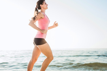 Running woman. Female runner jogging during the sunrise on beach