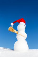 Schneemann mit roter Mütze und Besen im Schnee
