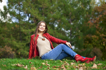 Hppy beautiful woman in red leather jacket and blue jeans sittin