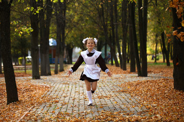 Fototapeta premium Happy little schoolgirl go home from school