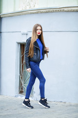 Young beautiful girl in blue jeans and a black leather jacket on