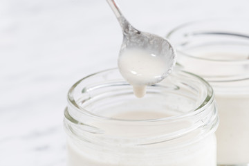 glass jar with fresh yogurt, closeup, selective focus