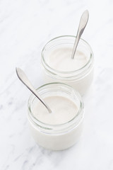 glass jars with fresh yogurt, top view, vertical