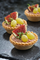 tartlets with liver pate and fruit on dark background, vertical