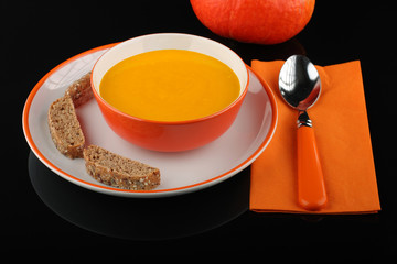  pumpkin hokkaido soup with bread  on white plate on black