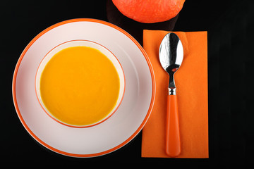 bowl of pumpkin hokkaido soup on white plate on black sheet