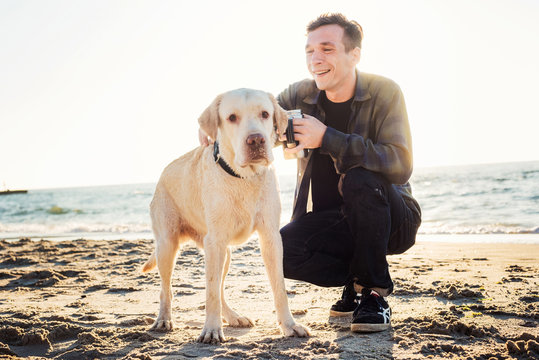 young caucasian male drinking coffee on beach while walking with