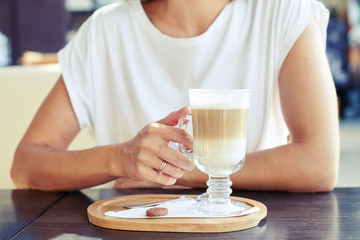 woman in white t-shirt holding cup of cappuccino