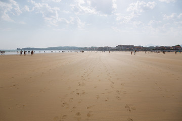 The sandy beach of the Atlantic Ocean. South of France. Basque Country. Hendaye. Blue sky with high clouds and yellow sand. horizon line in the middle. space for inscriptions. Backlit