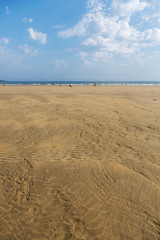The sandy beach of the Atlantic Ocean. South of France. Basque Country. Hendaye. Blue sky with high clouds and yellow sand. horizon line in the middle. space for inscriptions