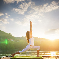 Woman doing yoga on the lake - beautiful lights