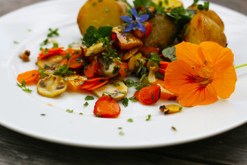 Veganes Mittagessen, Gemüse, Möhren, Paprika und Pilze und frische Kräuter mit Kartoffeln - Borretsch, Kapuzinerkresse (Tropaeolum), Essbare Blüten, gesunde Ernährung
