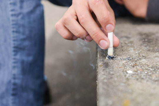 Hand of a young man extinguish cigarette on a stair