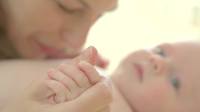 Mother kissing and hugging her newborn baby