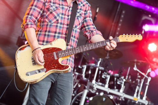 musician on stage strumming an electric guitar