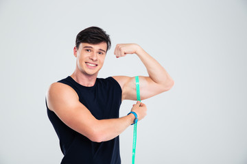 Portrait of a happy fitness man measuring his biceps